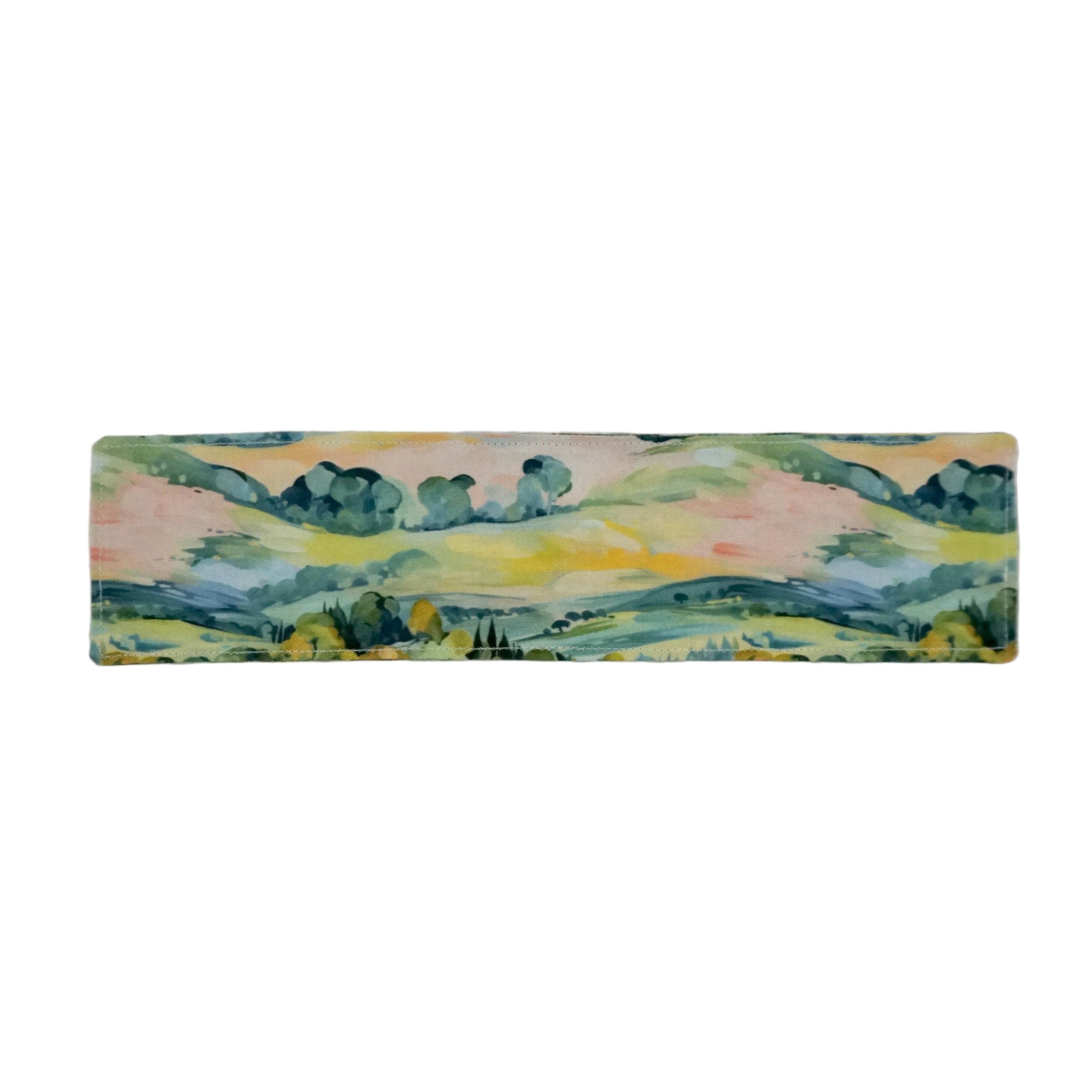 Fabric bookmark with a countryside scene in bright greens, blues, yellows, and pinks on a white background.