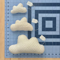 One each of a mini, extra small, and small cloud pillow on a blue cutting mat for scale.