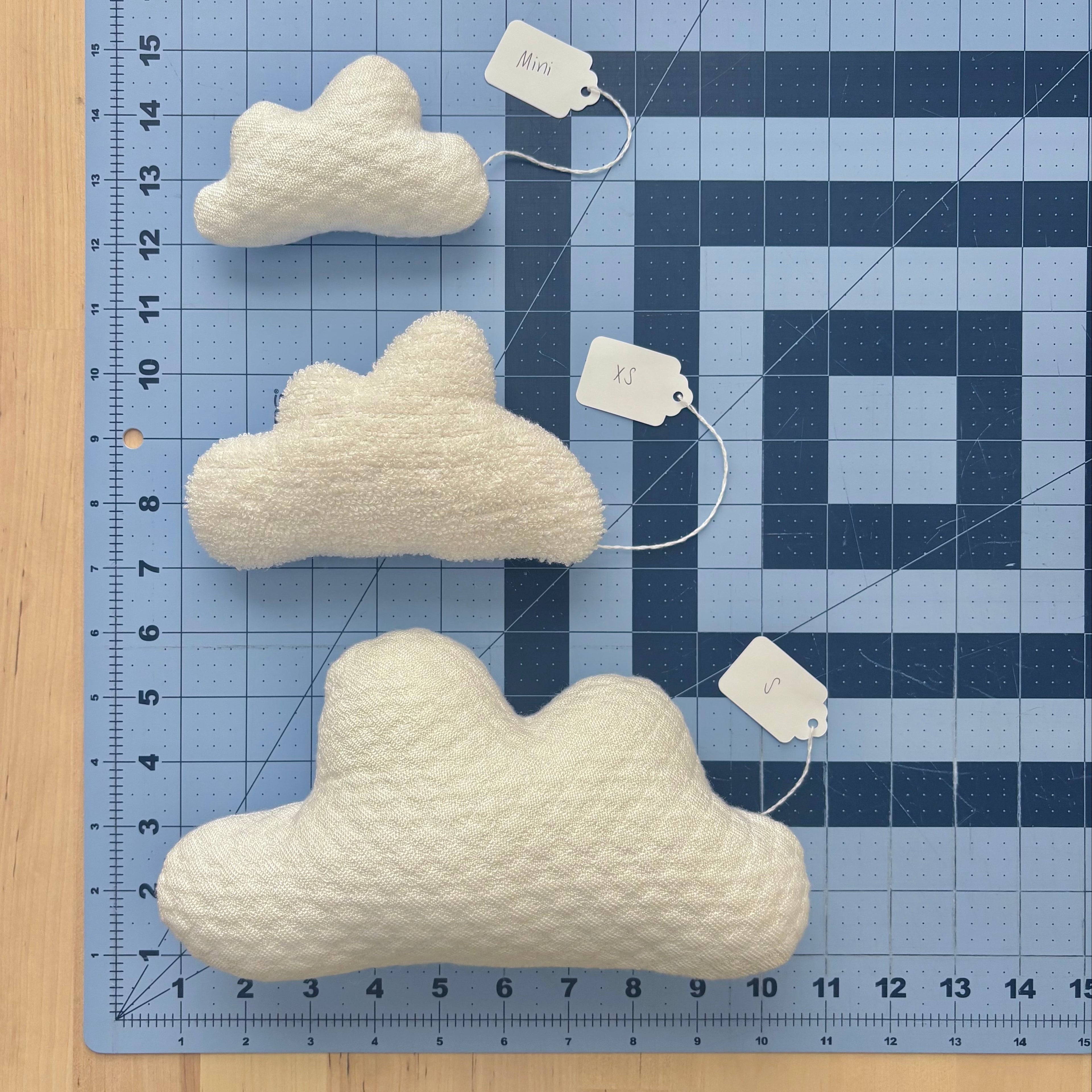 One each of a mini, extra small, and small cloud pillow on a blue cutting mat for scale.