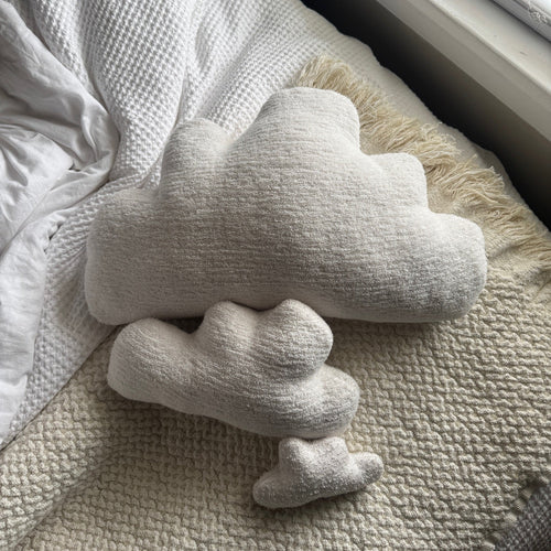 Three white cloud-shaped pillows seen from top down on a bed.