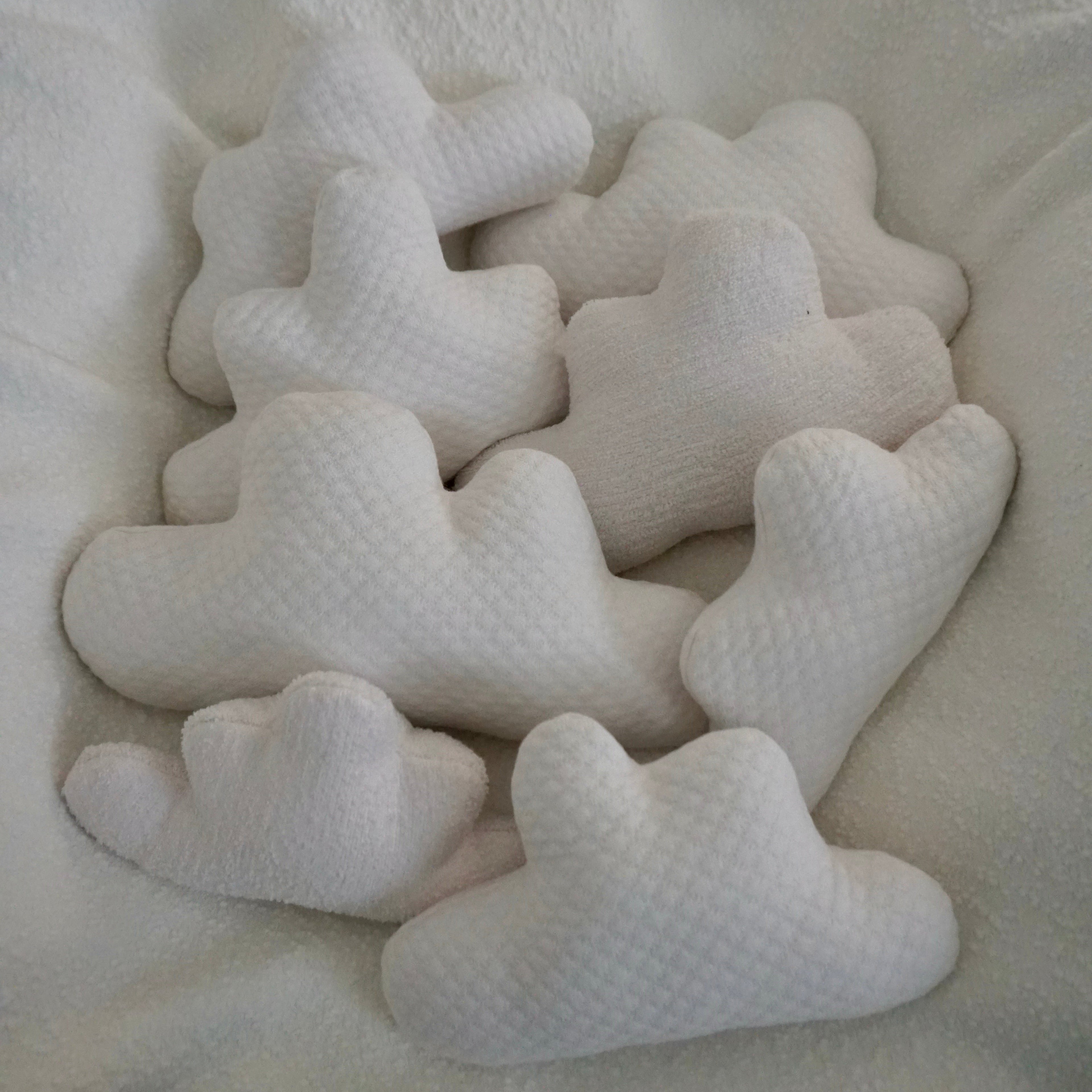 Eight medium Cloud Pillows arranged together on a chair with a white boucle blanket draped over it.