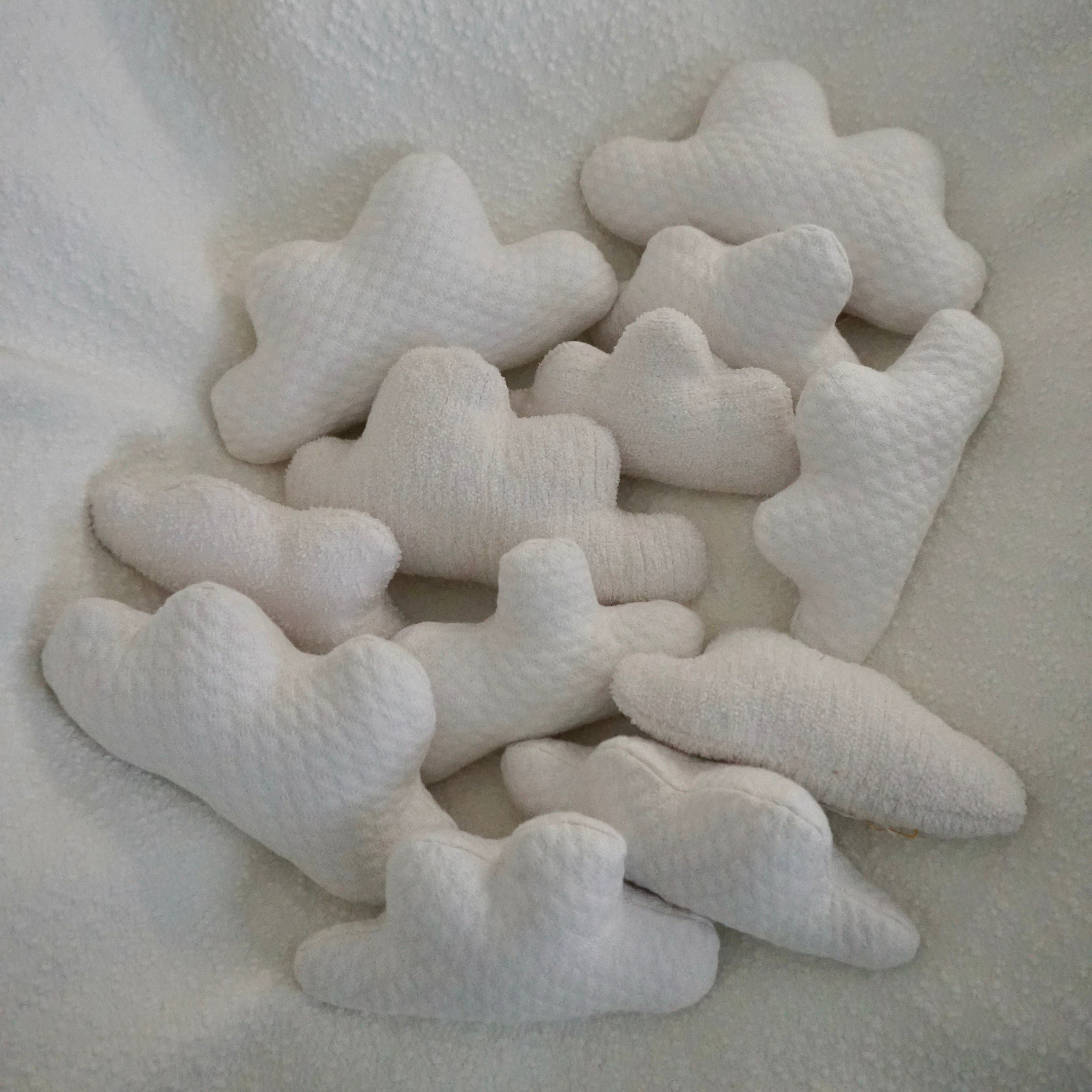 Twelve extra small Cloud Pillows on a textured white blanket.