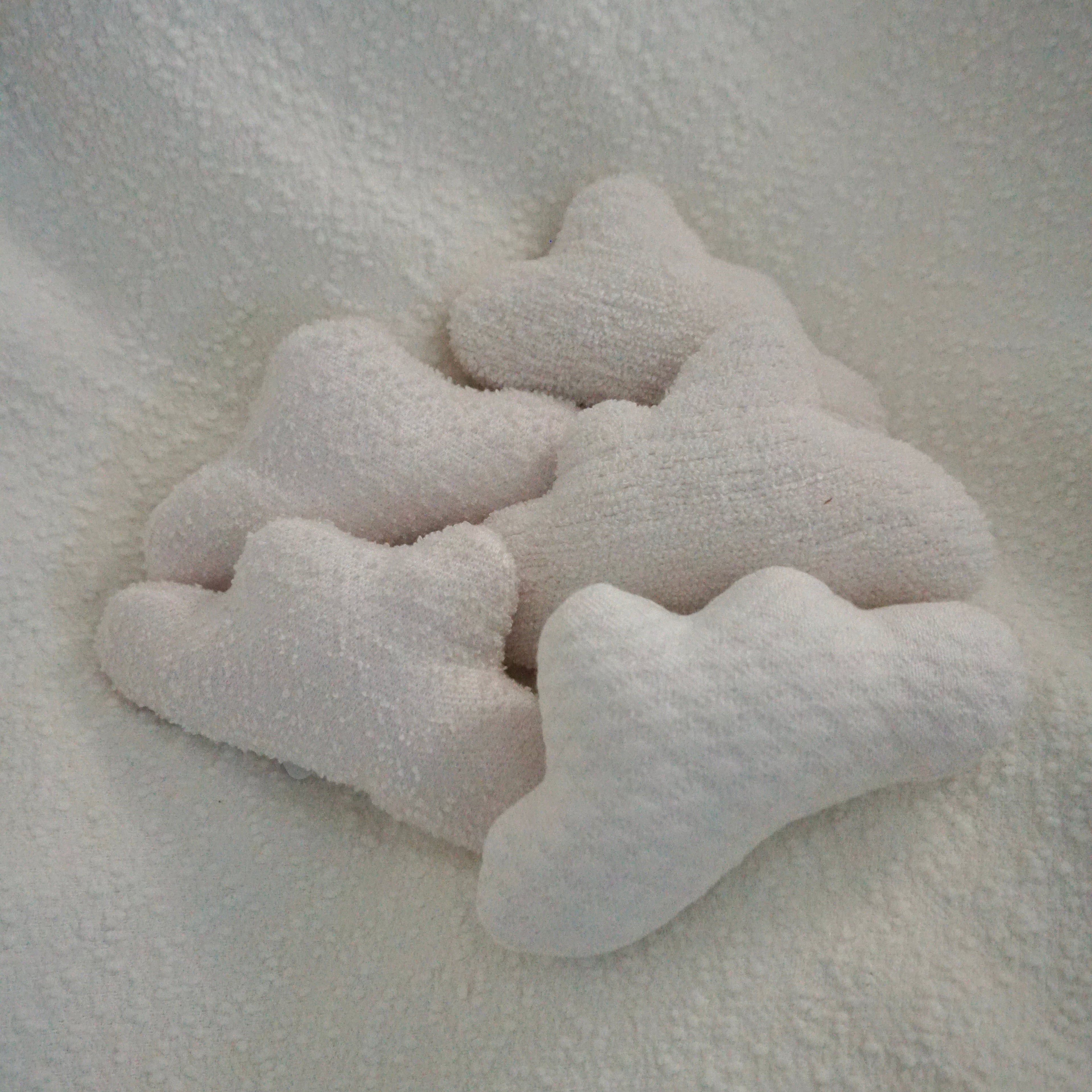 Five small Cloud Pillows arranged together on a textured white blanket.