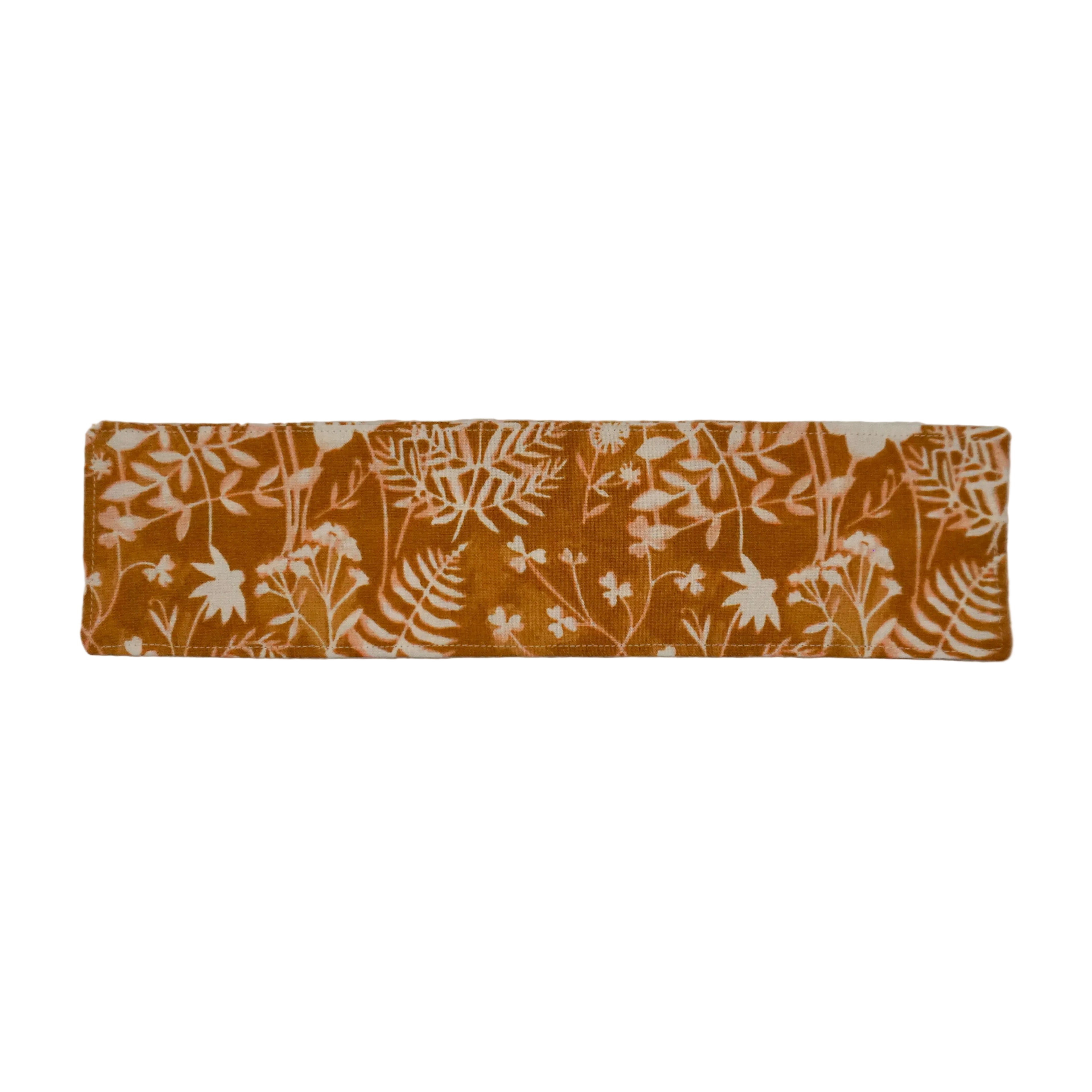 Orange fabric bookmark with white fern and floral pattern on a white background.