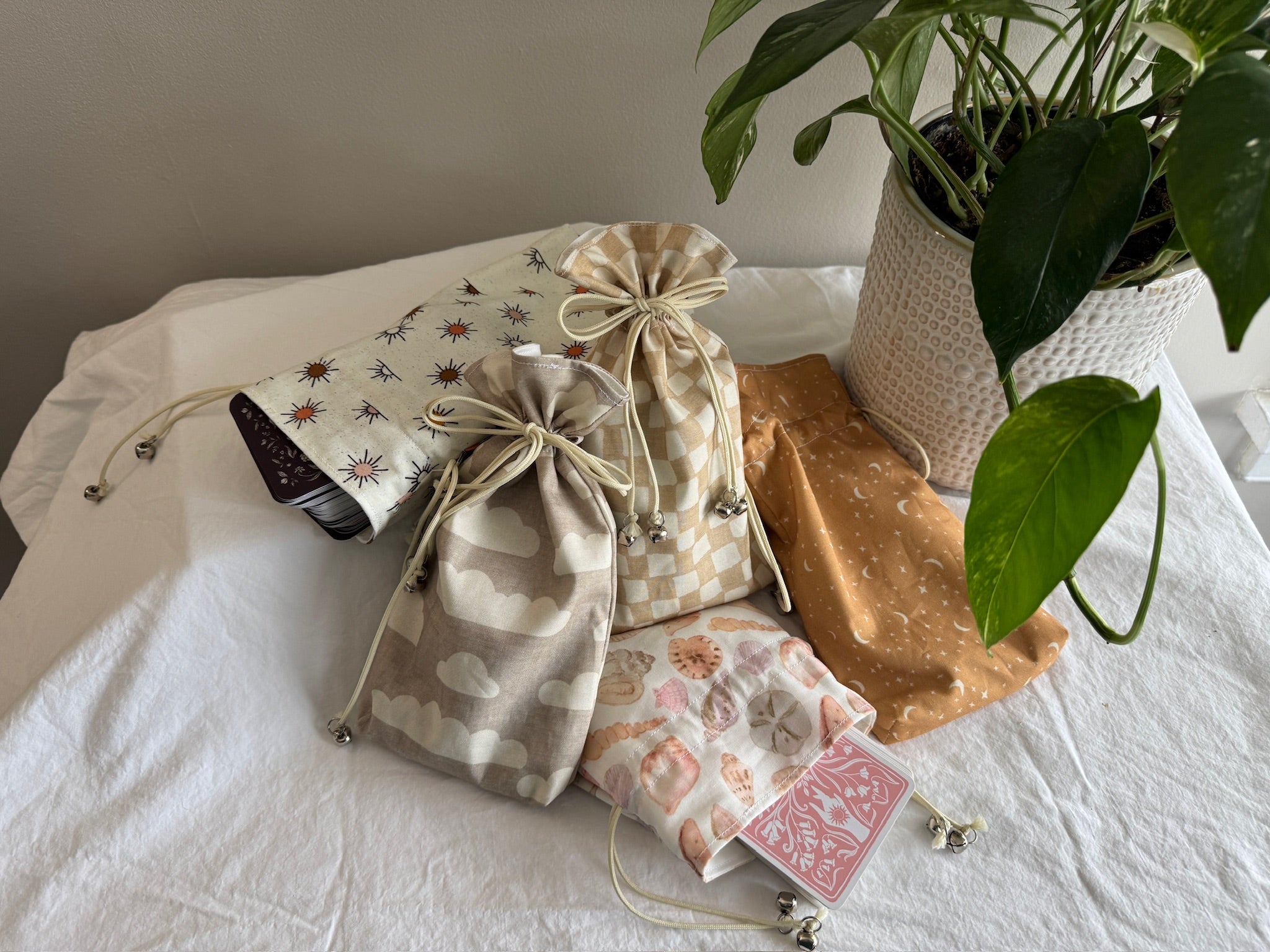 Set of patterned drawstring bags on a white surface with a plant in the background