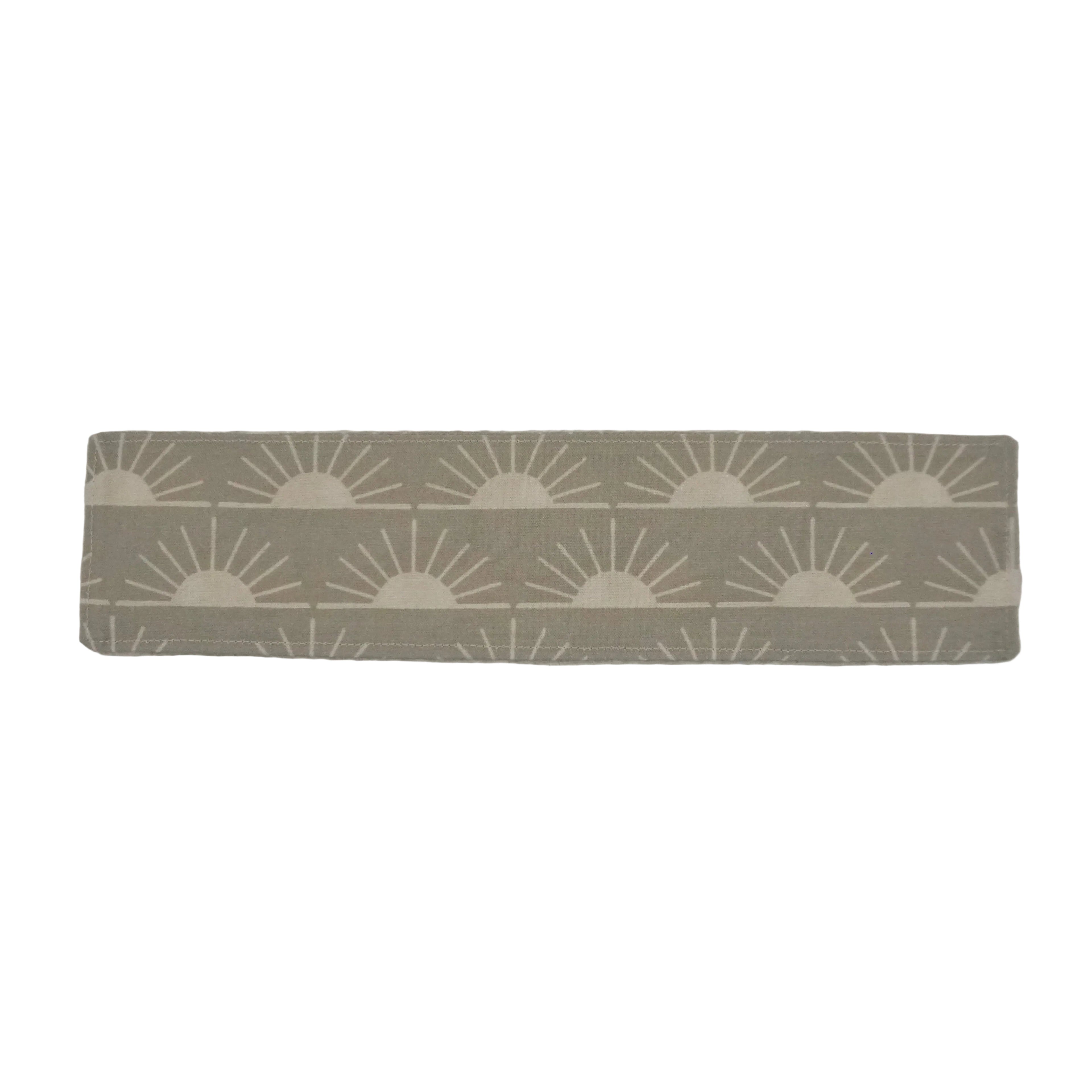 Sage green bookmark with off white sun pattern on a white background.