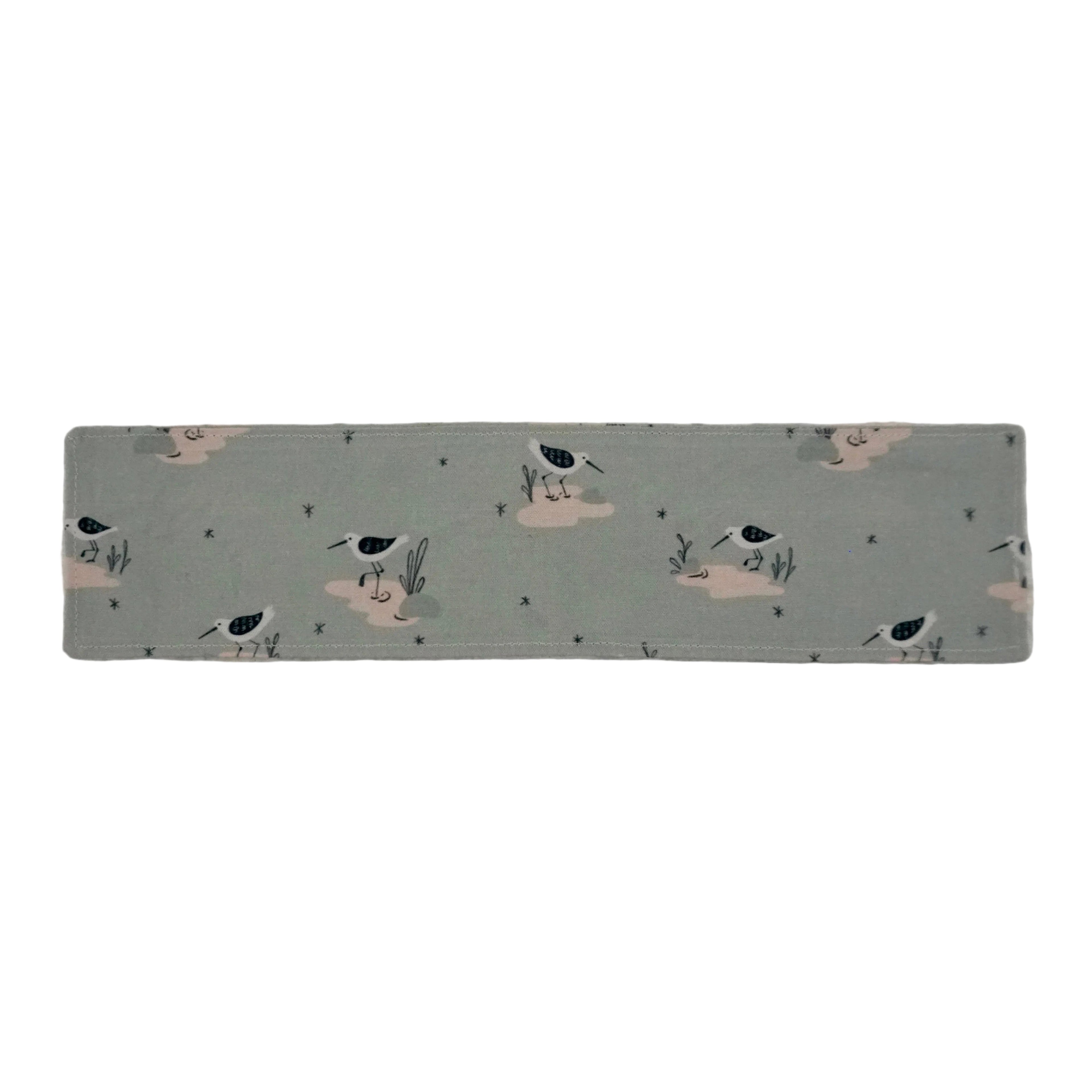 Dusty blue colored fabric bookmark with a drawn shorebird pattern on a white background.