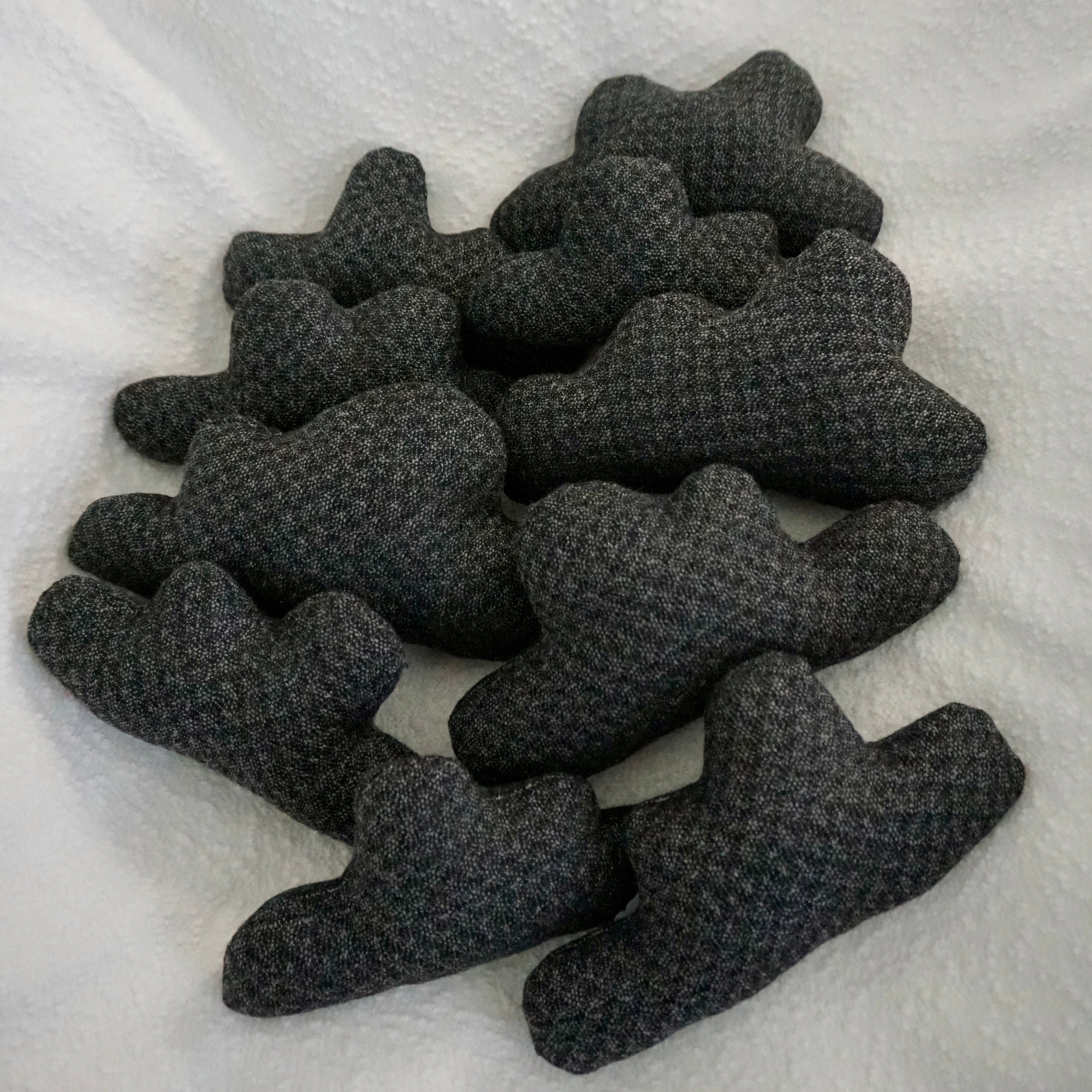 Ten storm cloud pillows made from a dark gray quilted fabric resting together on a white boucle blanket.