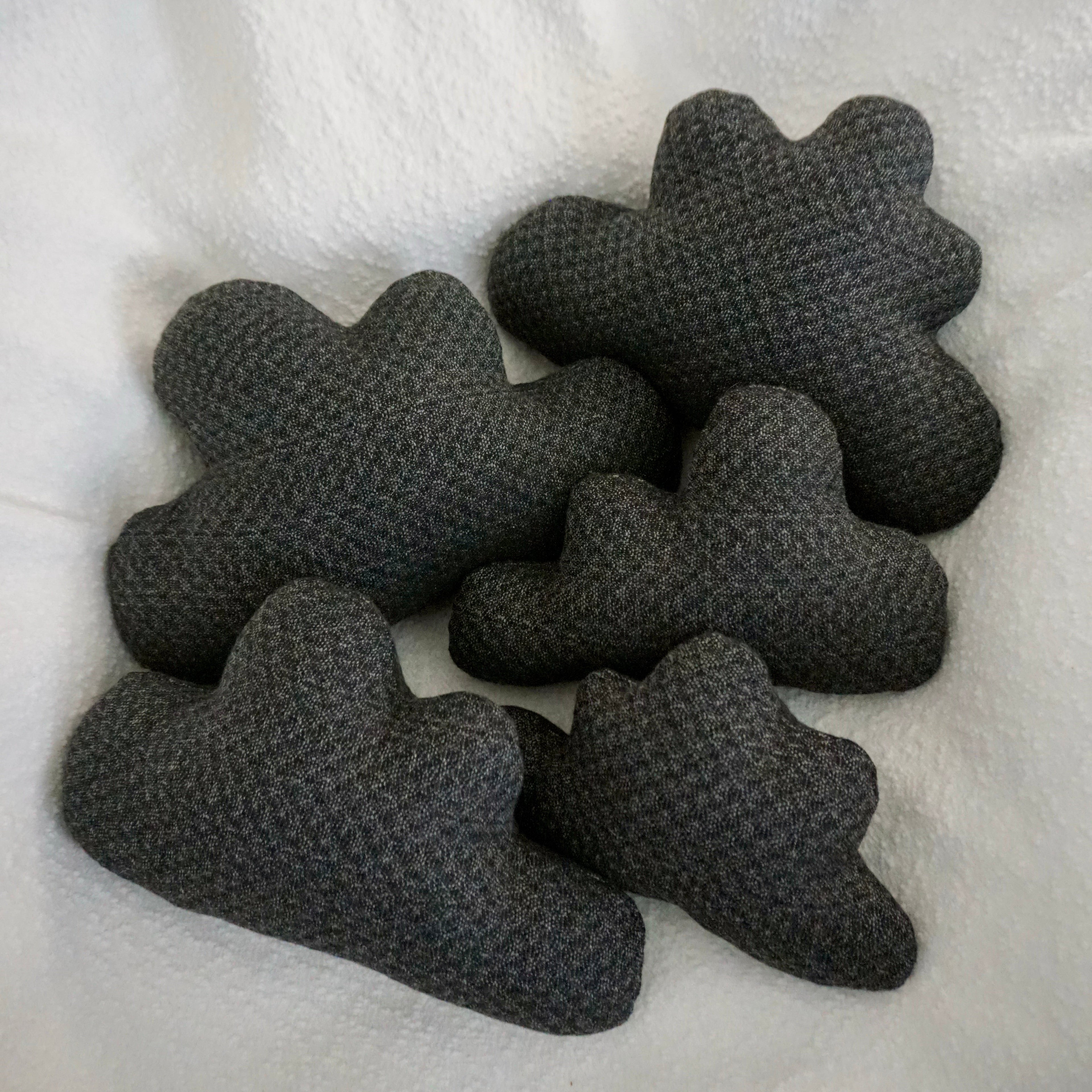 Five storm cloud pillows arranged together on a textured white blanket.