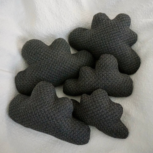 Five storm cloud pillows arranged together on a textured white blanket.
