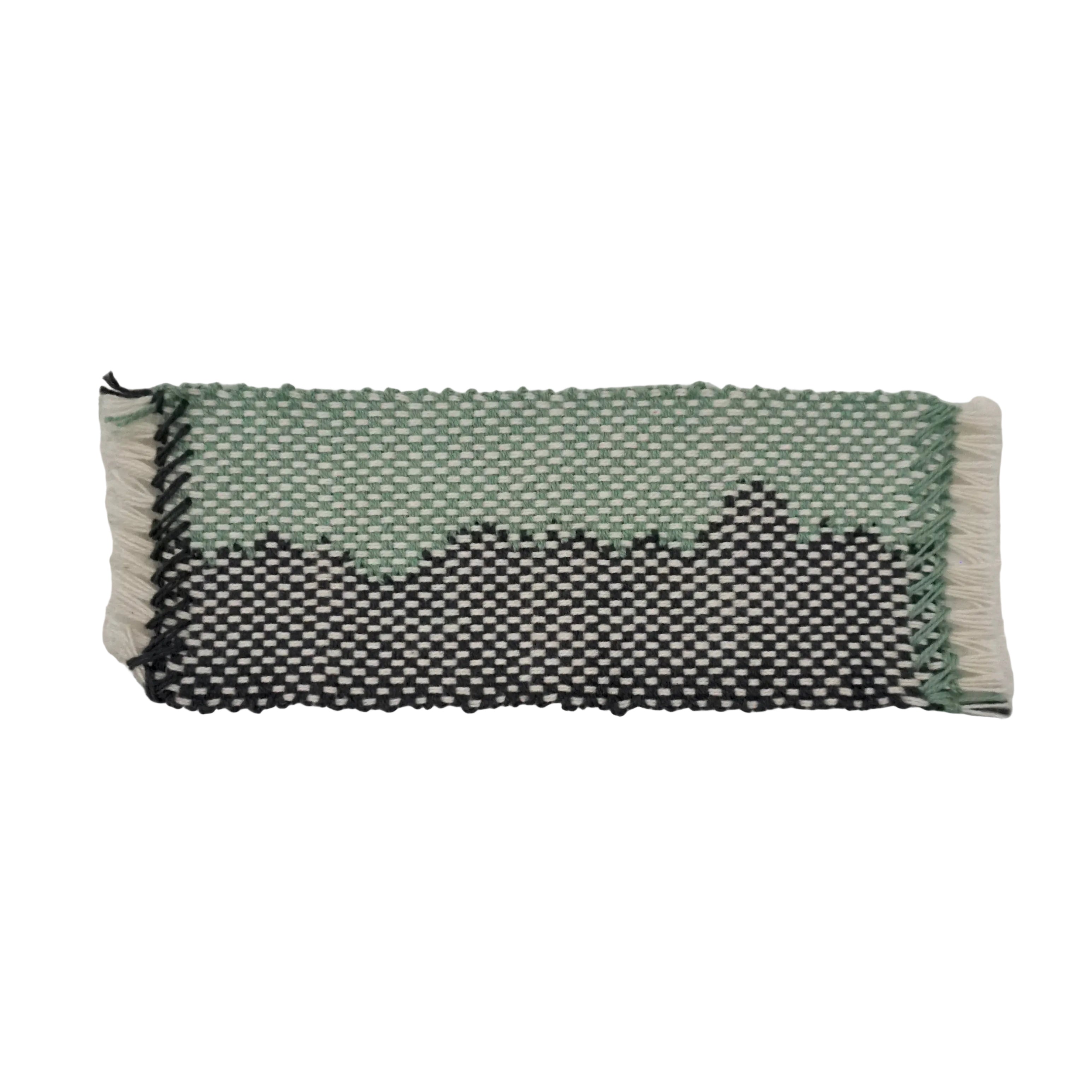 A sky blue and charcoal gray woven bookmark with white accents featuring a wavy design on a white background.